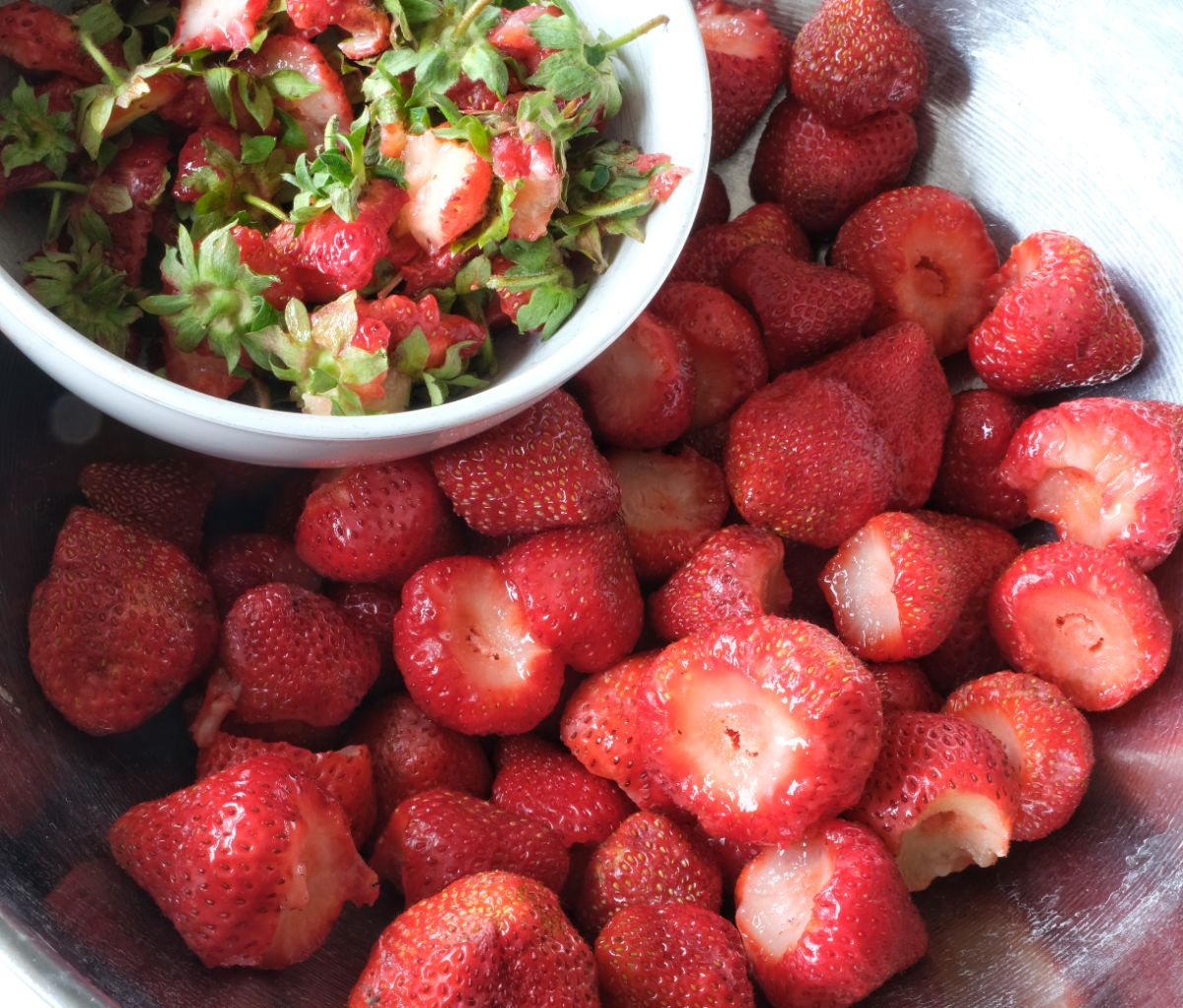 Hulled strawberries next to bowl full of remaints