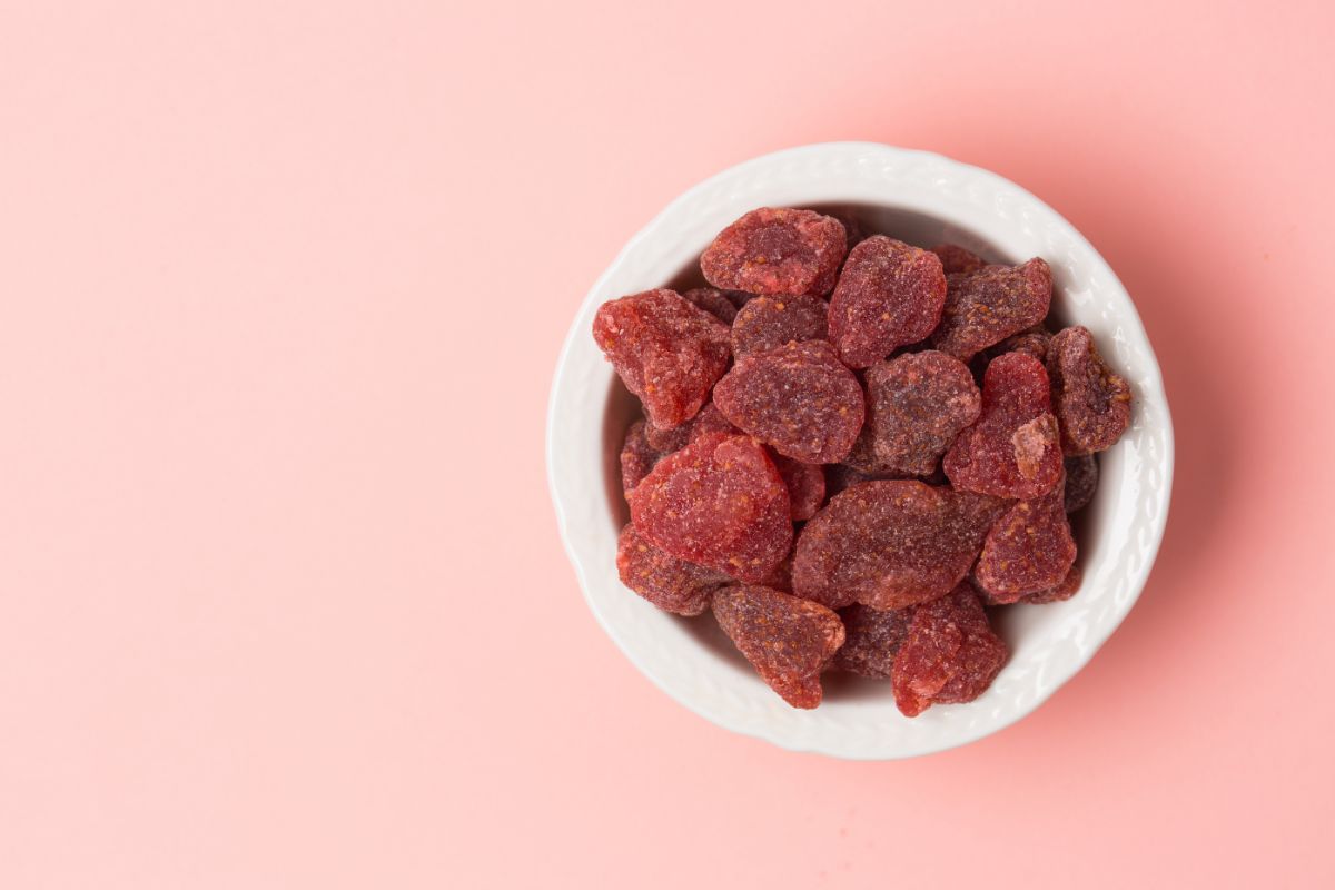 Sun dried strawberries in white bowl on pink background