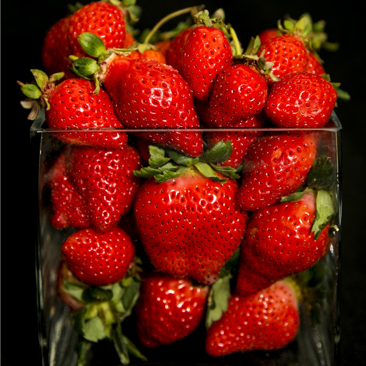 Caridal strawberries in glass black background