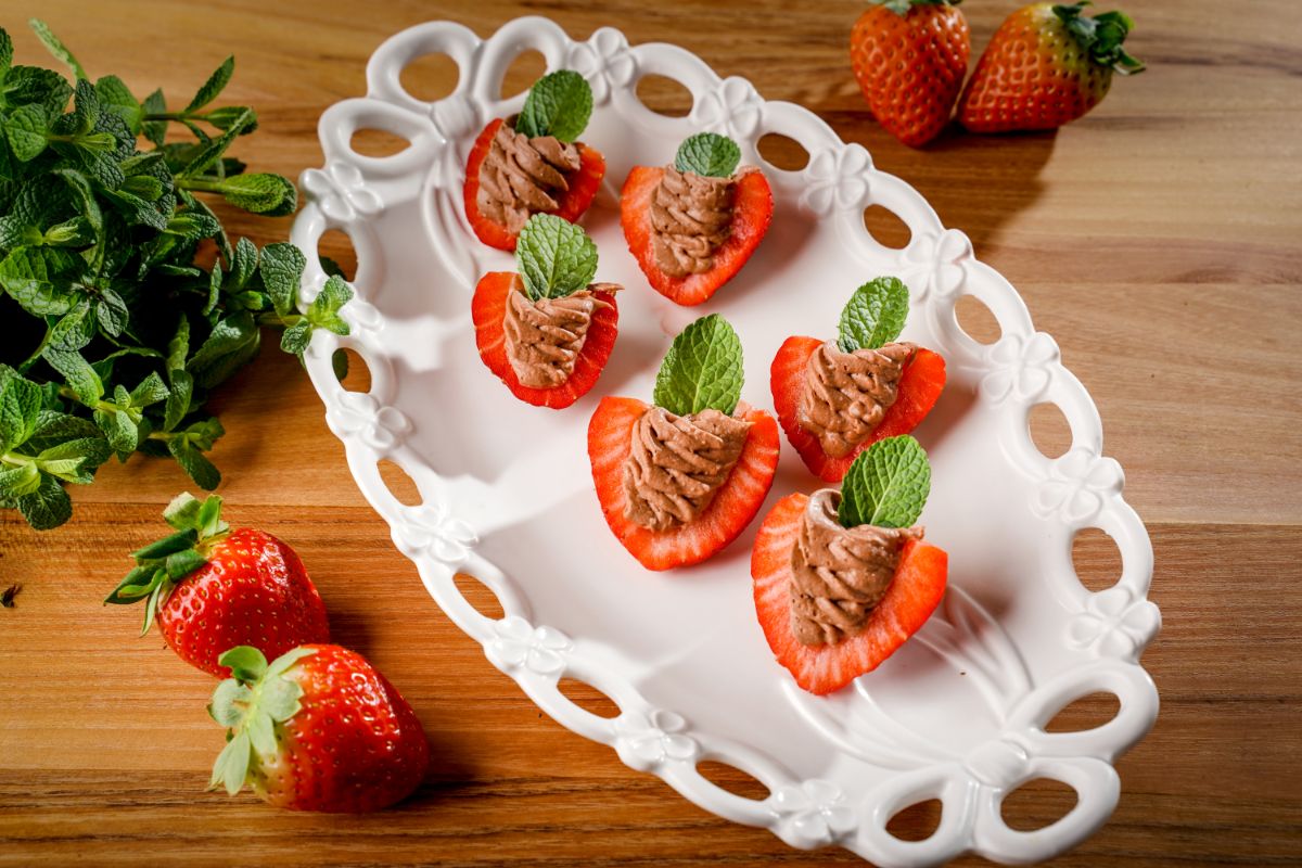 Deviled strawberries on a white tray with ripe strawberries around.