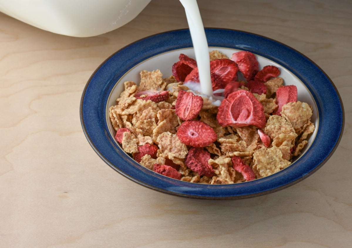 Adding dried strawberries to morning cereal.