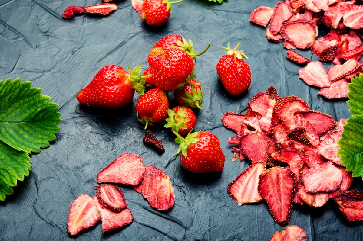 Dried and fresh strawberries on a desk.
