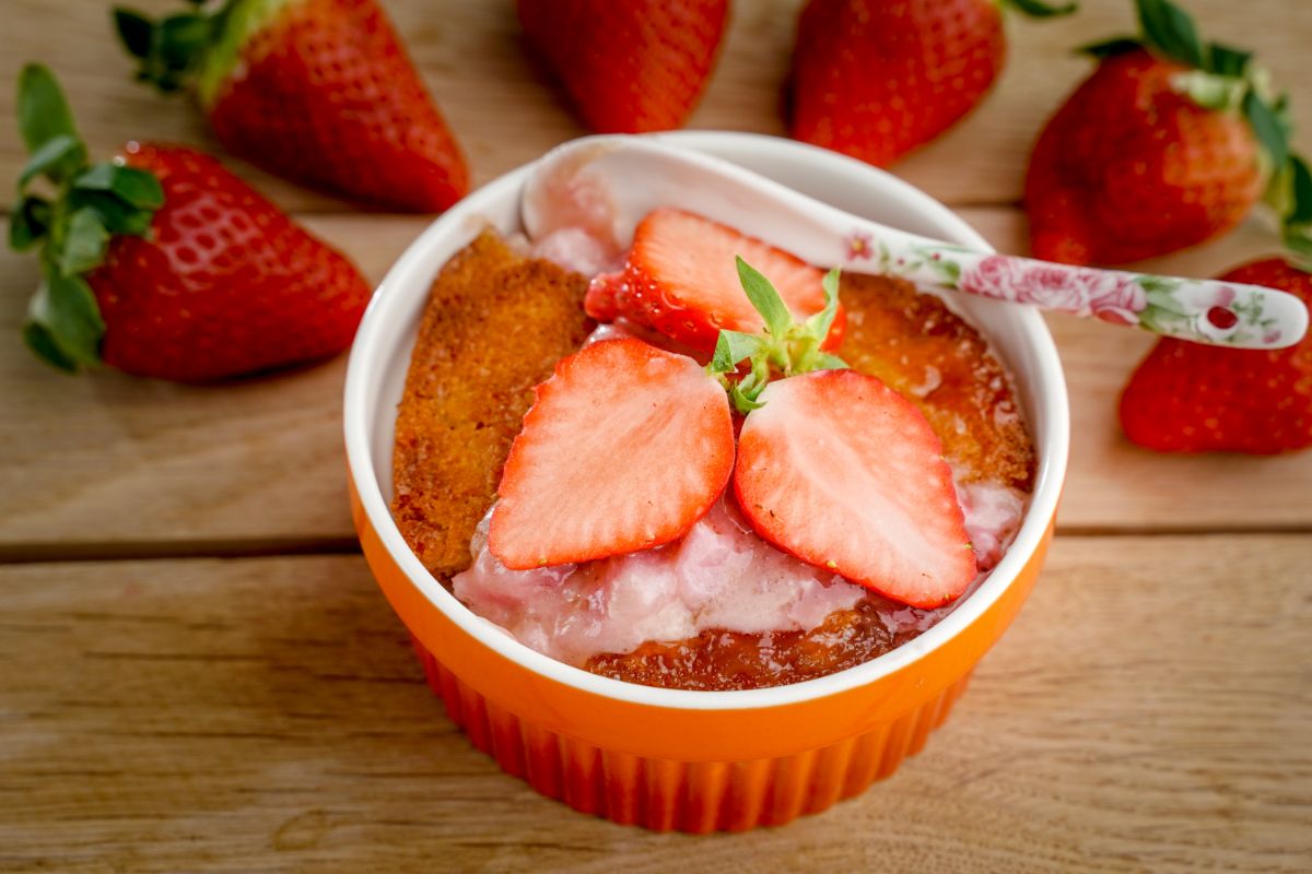 Fresh strawberry cobbler in a bowl with sliced strawberries.