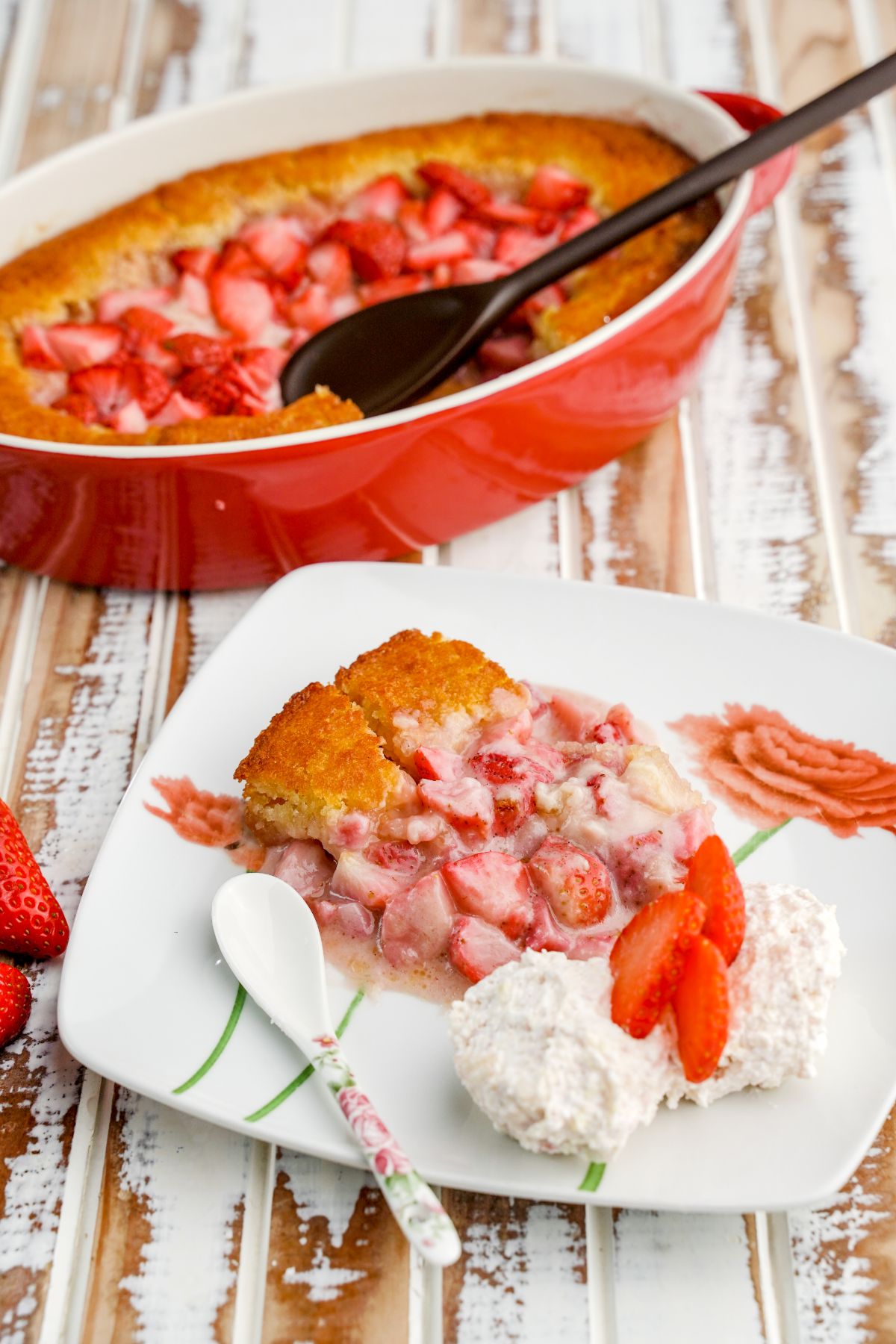 Fresh strawberry cobbler in  a white palte with strawberries and cream.