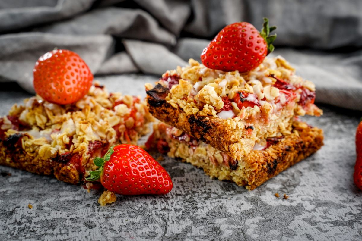 Healthy strawberry oatmeal bars with ripe strawberries on a table.