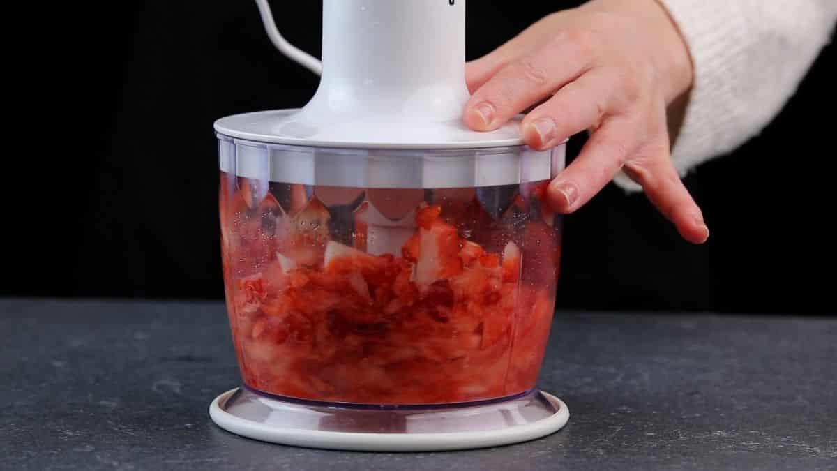 Strawberries being mixxes into puree.