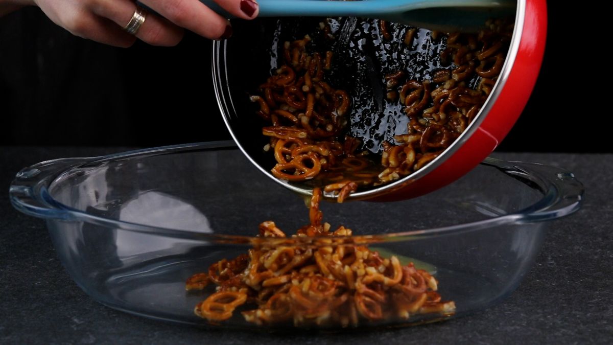 Putting pretzels into a glass container from pan.,