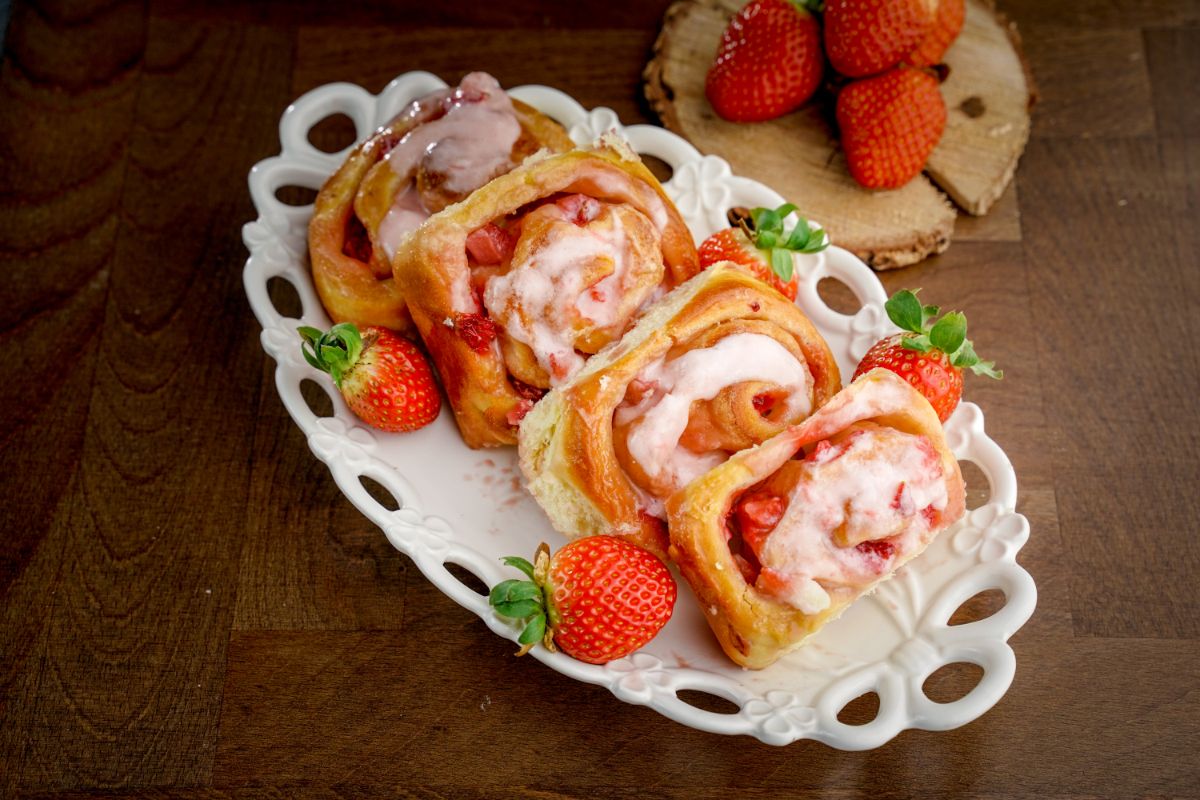 Strawberries and Cream Sweet Rolls on a white tray with ripe strawberries around.