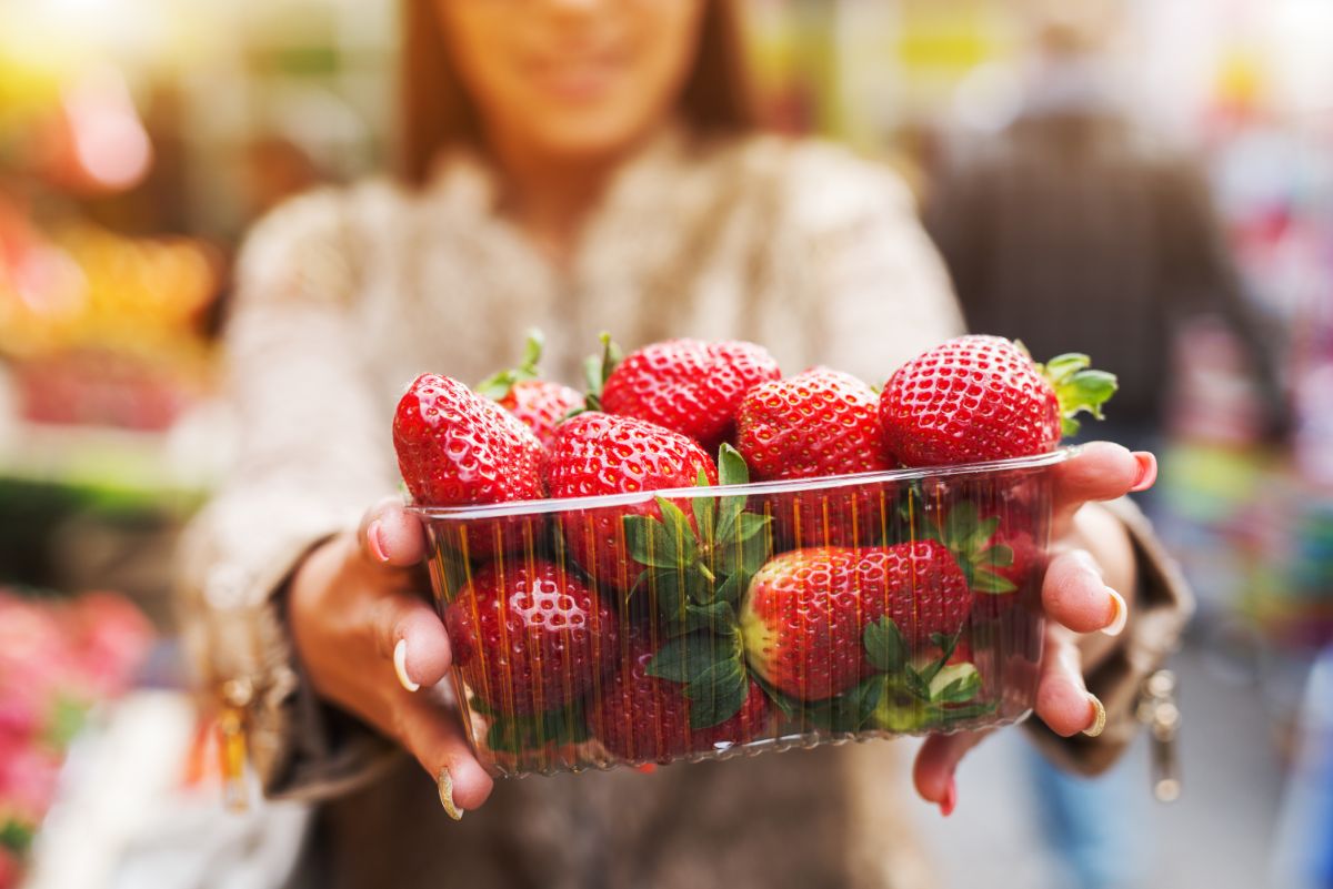 Woman hodling platic container full of strawberries