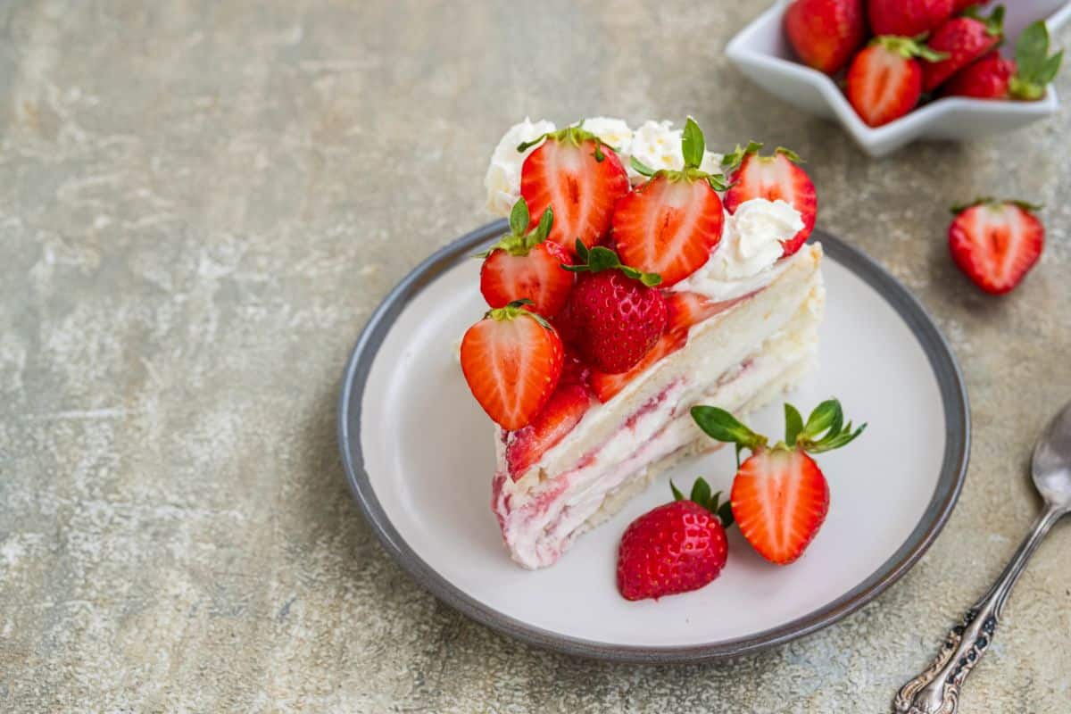 A piece of strawberry cake with fresh strawberries