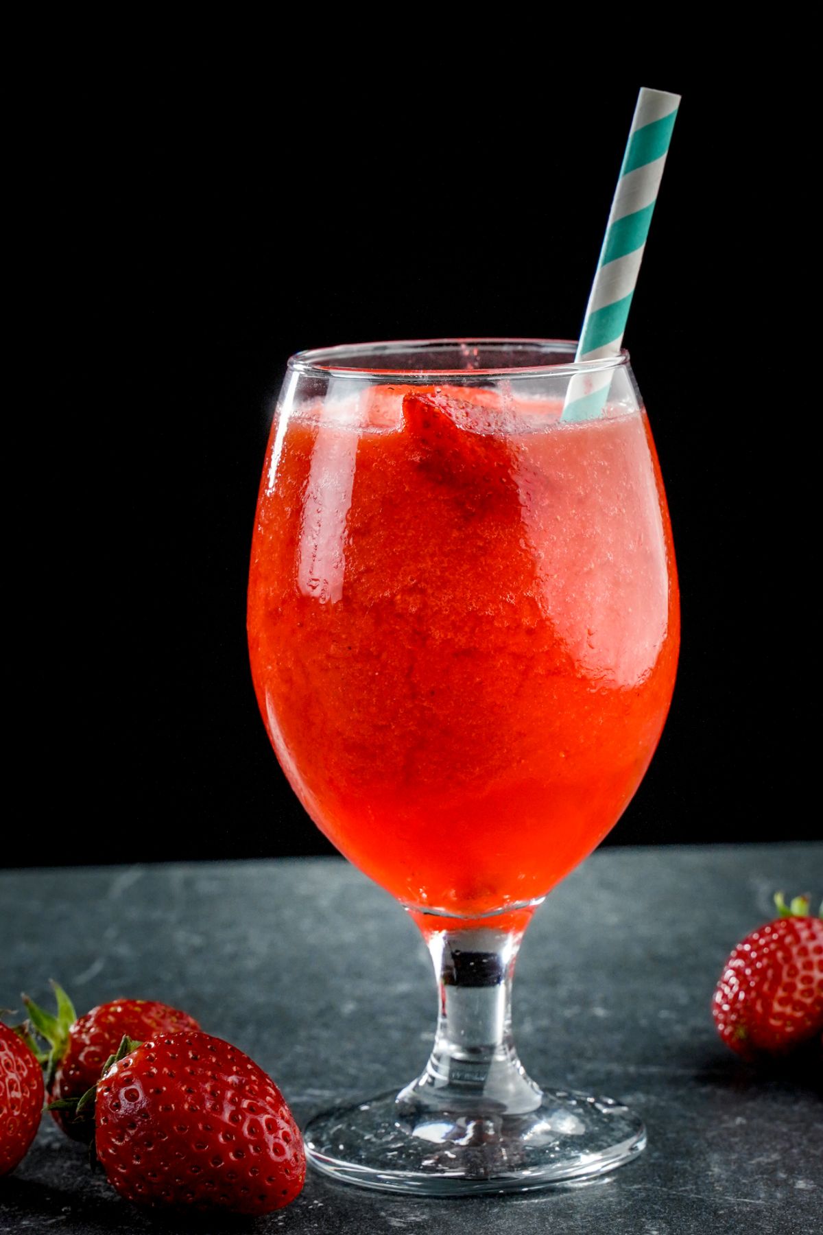 Strawberry daiquiri in a glass shot with a straw.