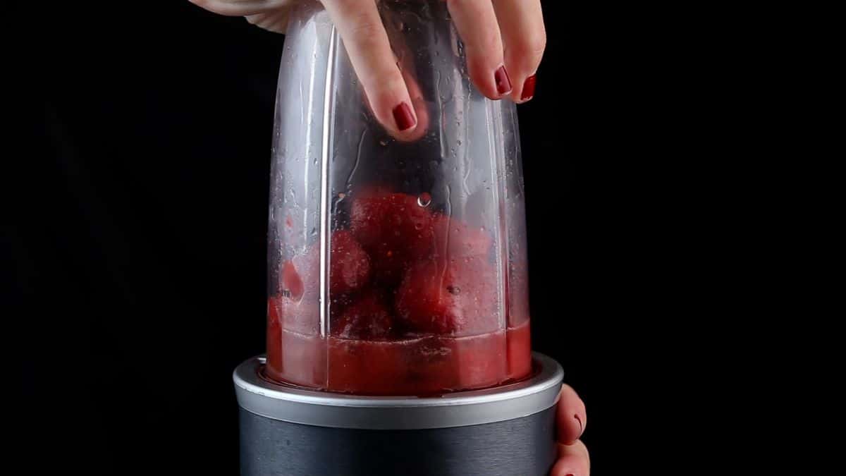 Blending strawberries and ice cubes in a blender.