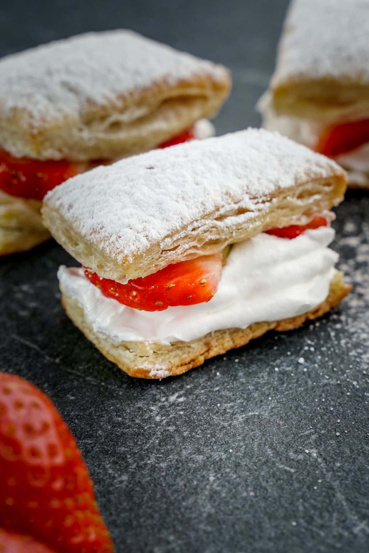 A close-up of strawberry shortcake puffs on a black tray.