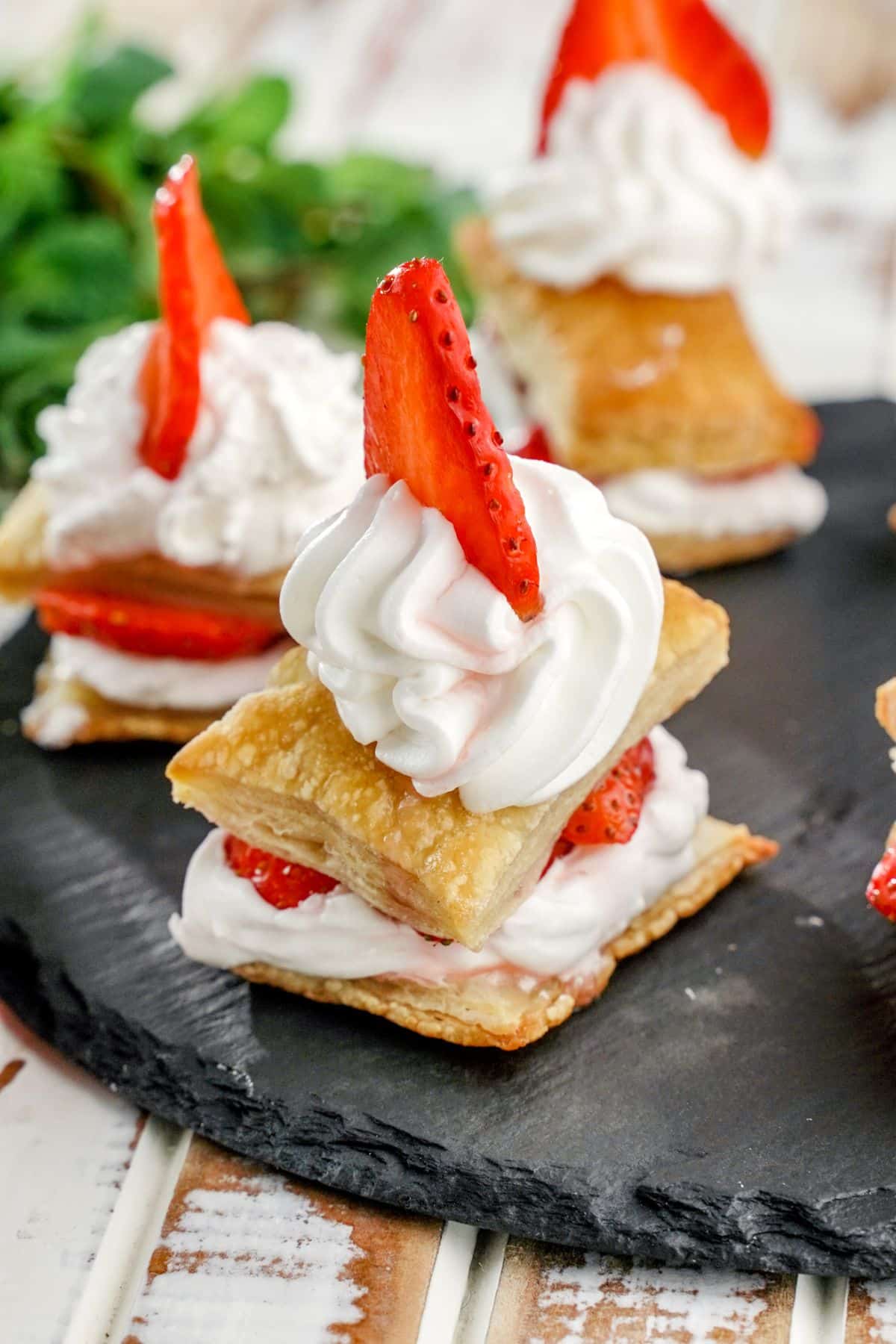 A close-up of strawberry shortcake puffs on a black tray.