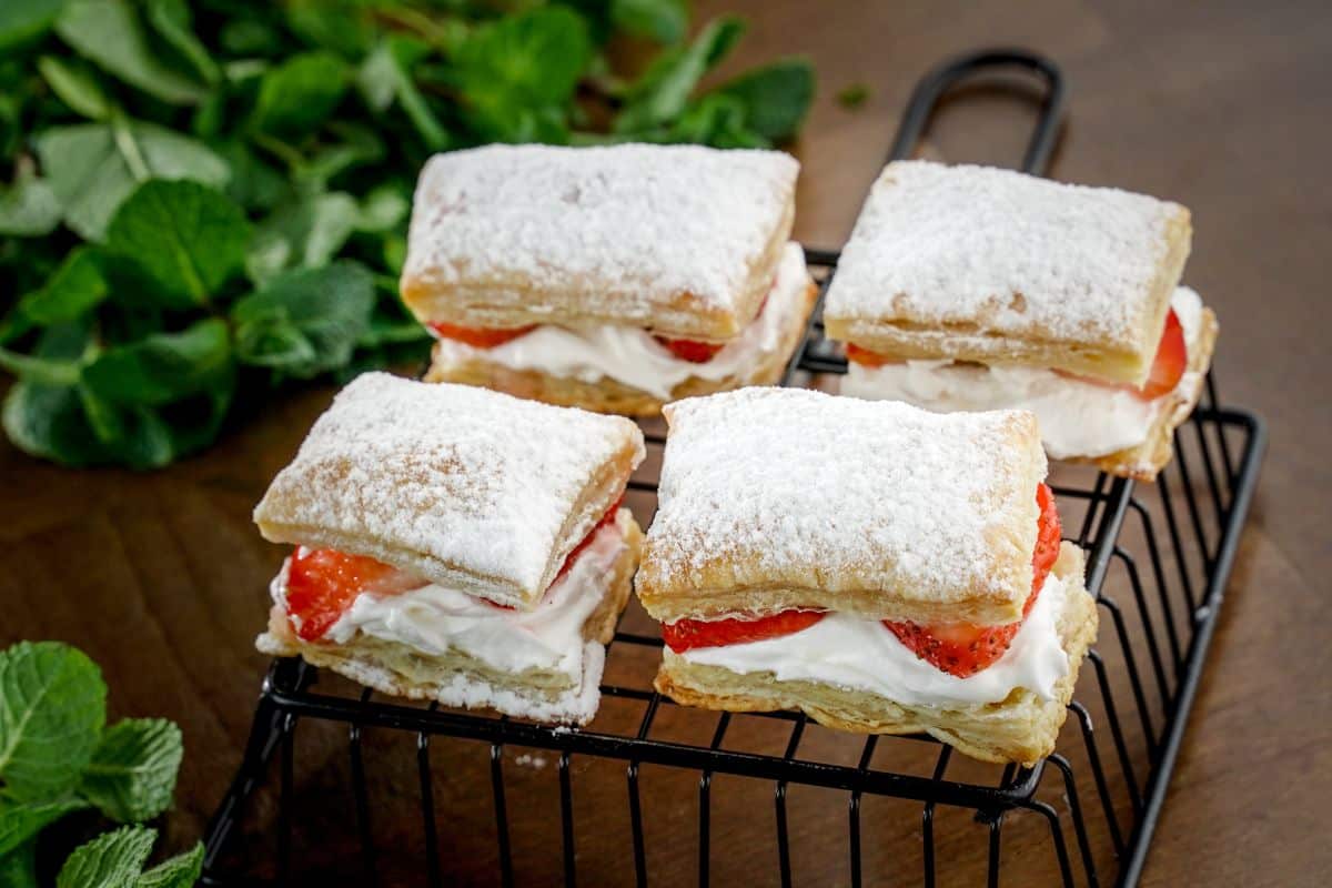 Four strawberry shorcake puffs on a black backing rack.