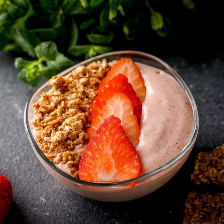 Strawberry vanilla smoothie bowl with sliced strawberries and a granola.