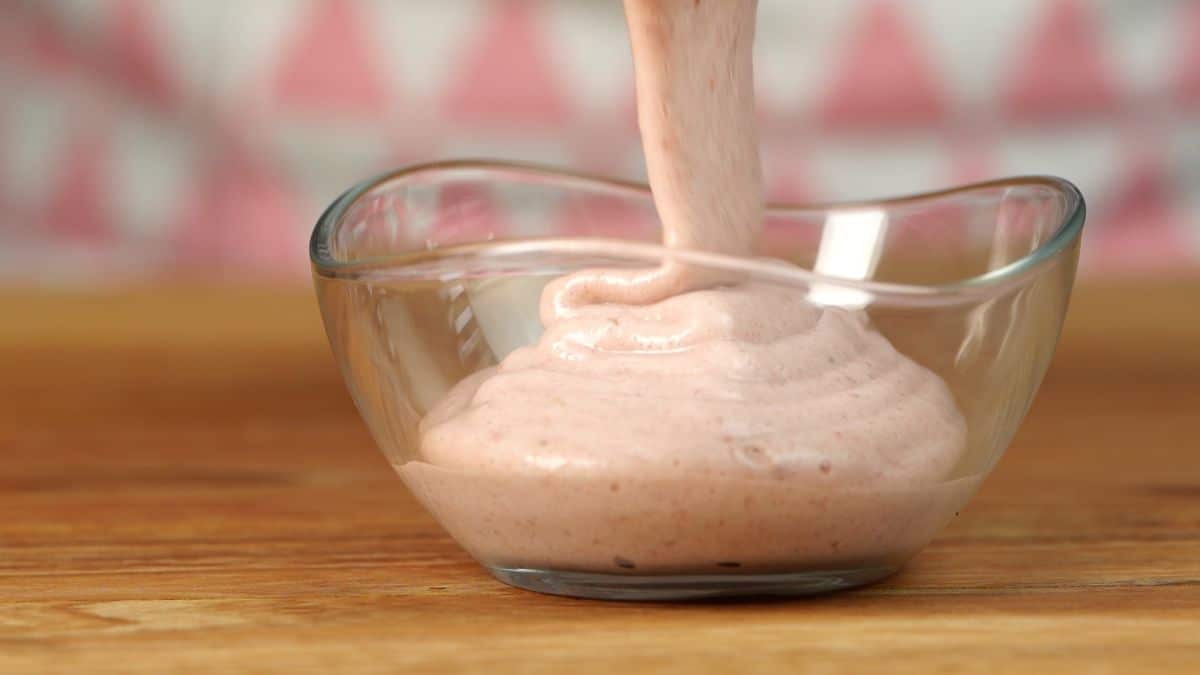Pouring strawberry vanilla smoothie into a bowl.