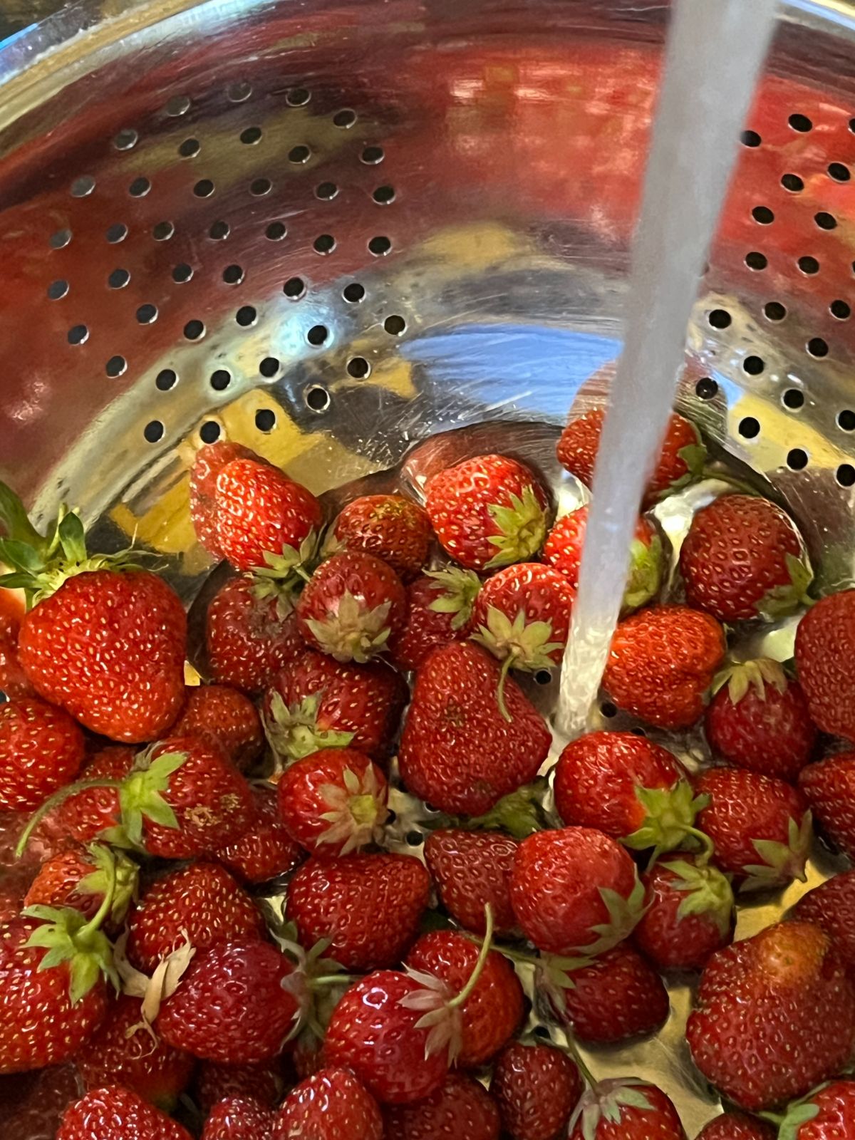 A closeup of strawberries being washed under running water